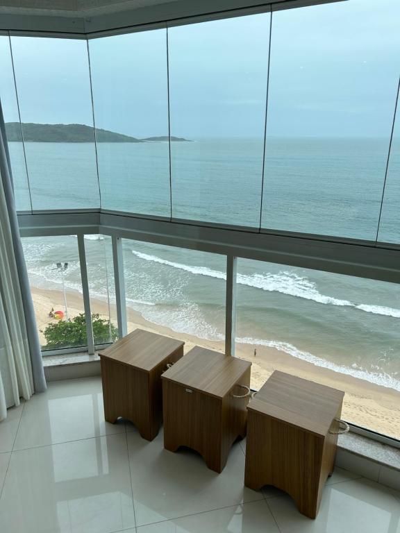 two benches in a room with a view of the beach at Apartamento de frente para o mar Praia do Morro Guarapari in Guarapari