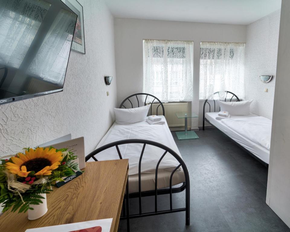 a room with two beds and a table with a vase of flowers at Hotel Tanne in Saalfeld