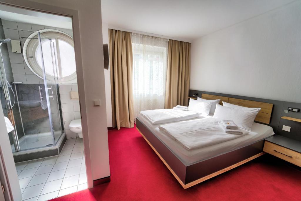 a bedroom with a bed and a bathroom with a shower at Hotel Tanne in Saalfeld