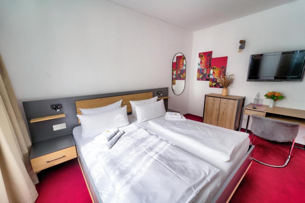 a bedroom with a large white bed and a television at Hotel Tanne in Saalfeld