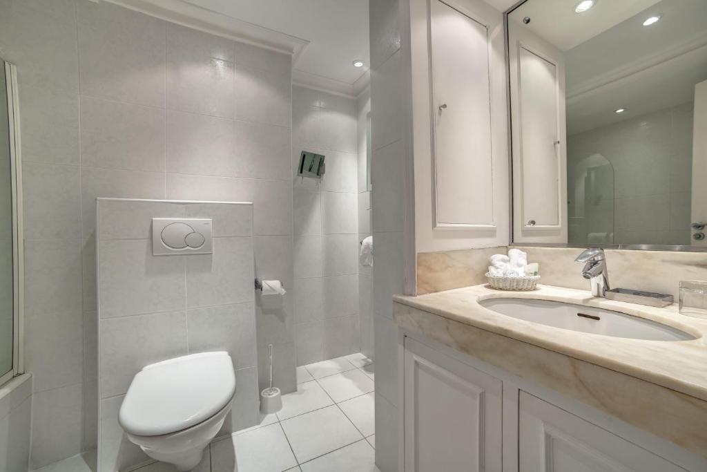 a bathroom with a toilet and a sink and a shower at Hôtel Victoria in Cannes