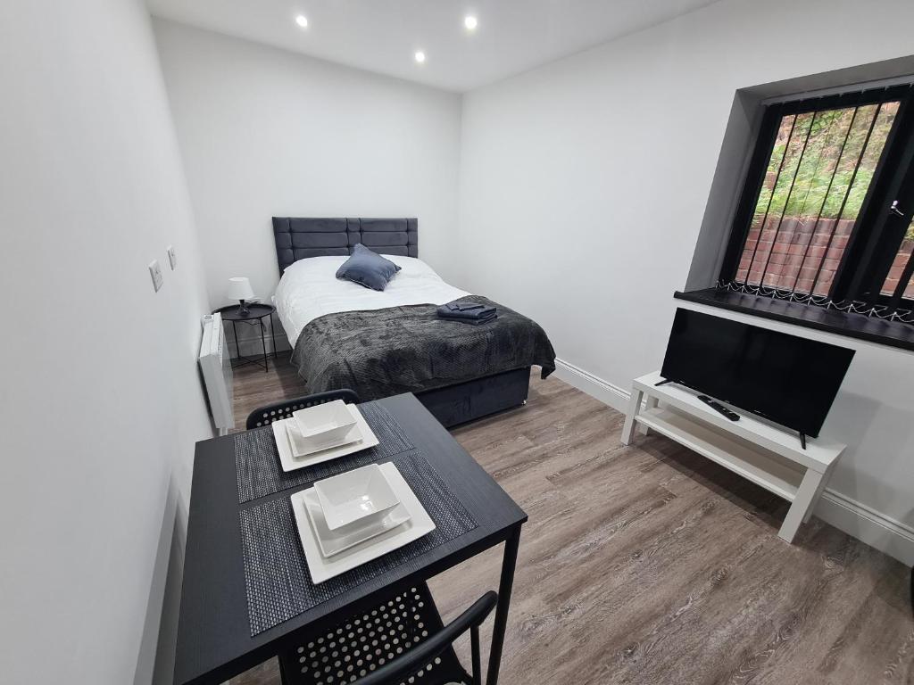 een slaapkamer met een bed, een tafel en een televisie bij Homestay by BIC Legends 4 in Batley Carr