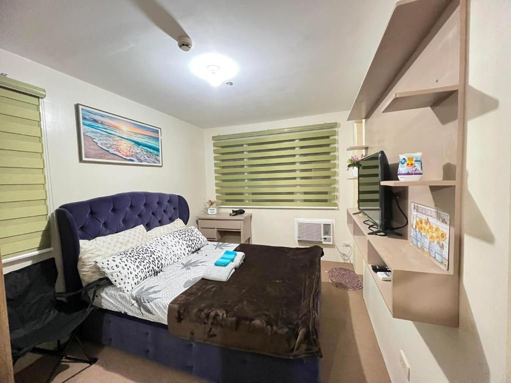 sypialnia z niebieskim łóżkiem i biurkiem z telewizorem w obiekcie Jay's Condo - Seawind w mieście Davao