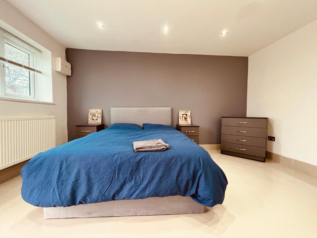a bedroom with a blue bed and two night stands at Large and comfy studio flat C near Heathrow in New Bedfont