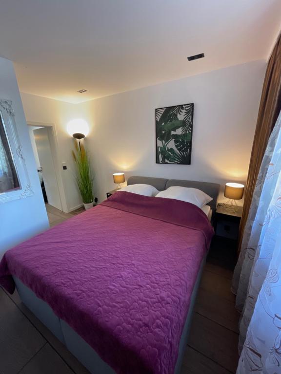 een slaapkamer met een groot bed en een paarse deken bij MYSTAY BERLIN Müggelheim in Berlijn