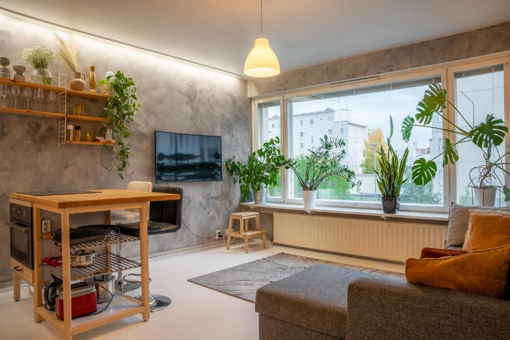 a living room with a table and a window with plants at Arctic Circle Retreat: Stylish 2-Room Apartment in Rovaniemi