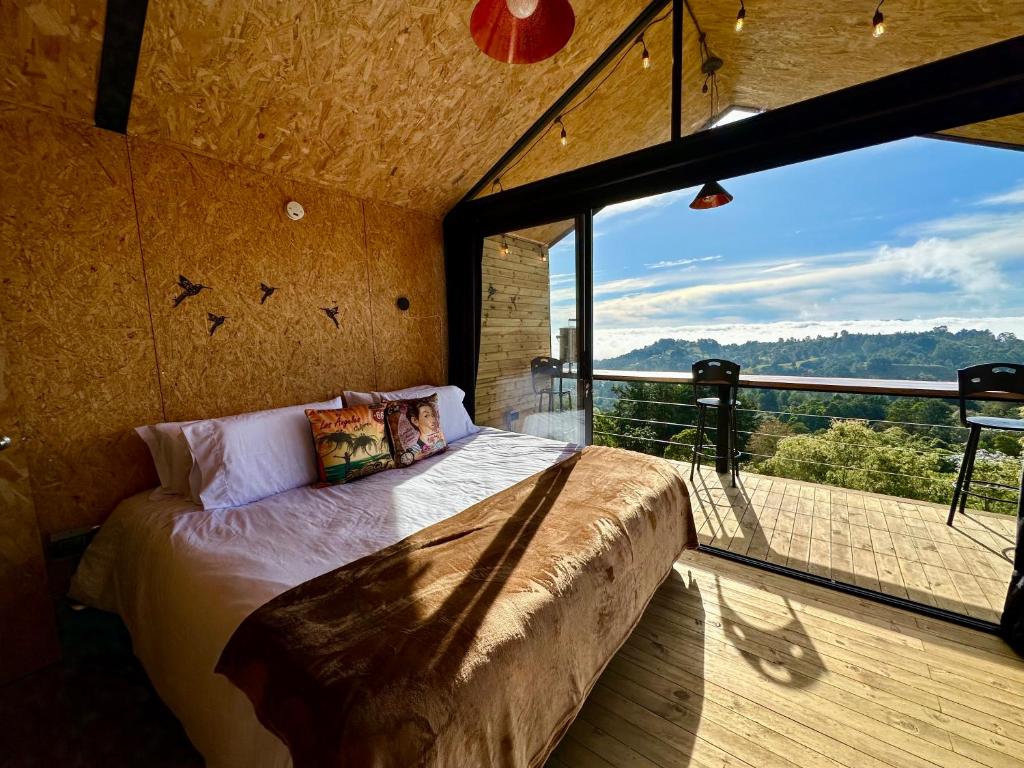 a bedroom with a bed and a large window at Caralsol Glamping in Rionegro