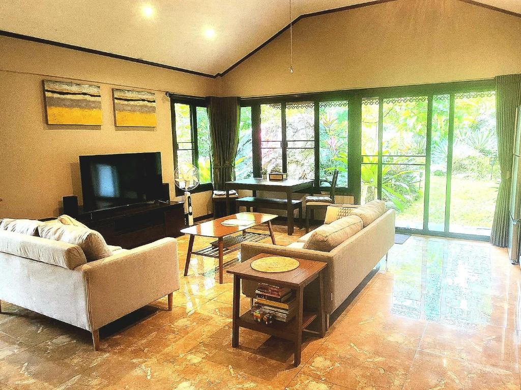 a living room with two couches and a television at UTOPAI Stone Garden Vacation Home, Pai! in Ban Muang Soi