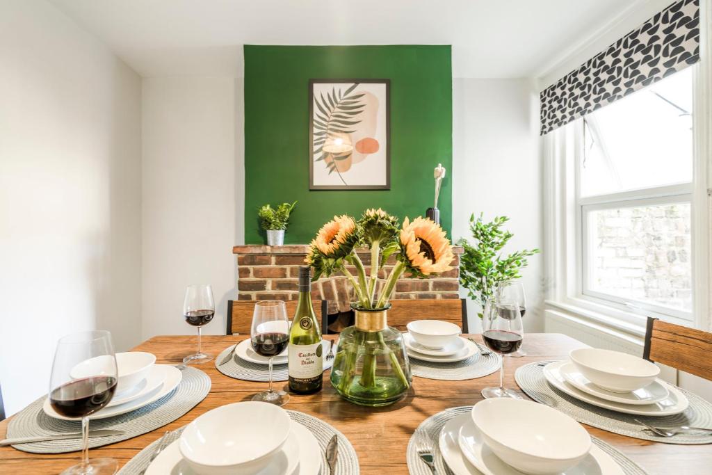 uma mesa de jantar com pratos brancos e copos de vinho em West Lodge- Cosy home from home with 3 bedrooms em Worthing