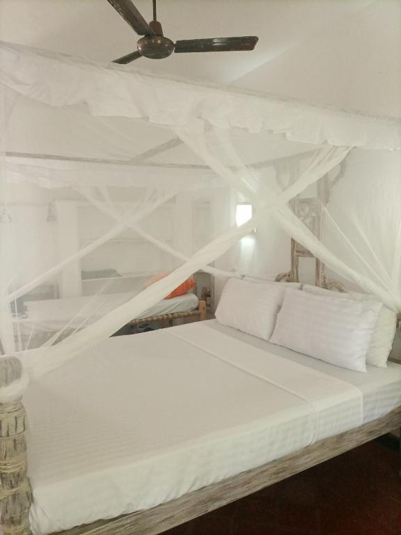 1 cama blanca con sábanas blancas y techo en Sophia house, en Malindi