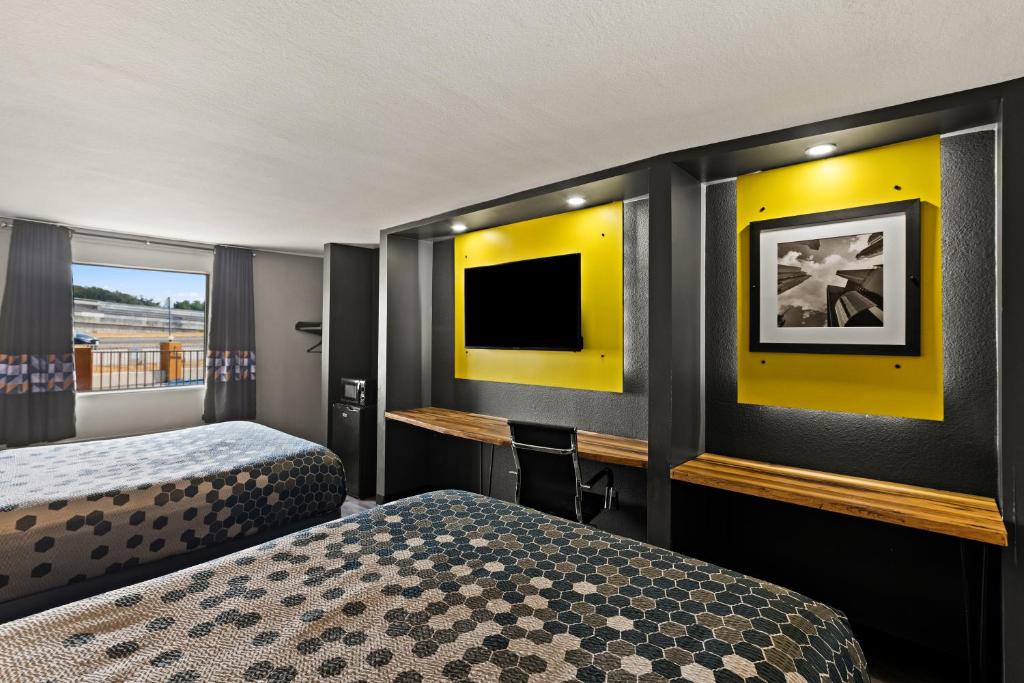 a hotel room with two beds and a flat screen tv at Scottish Inns Austin Downtown in Austin