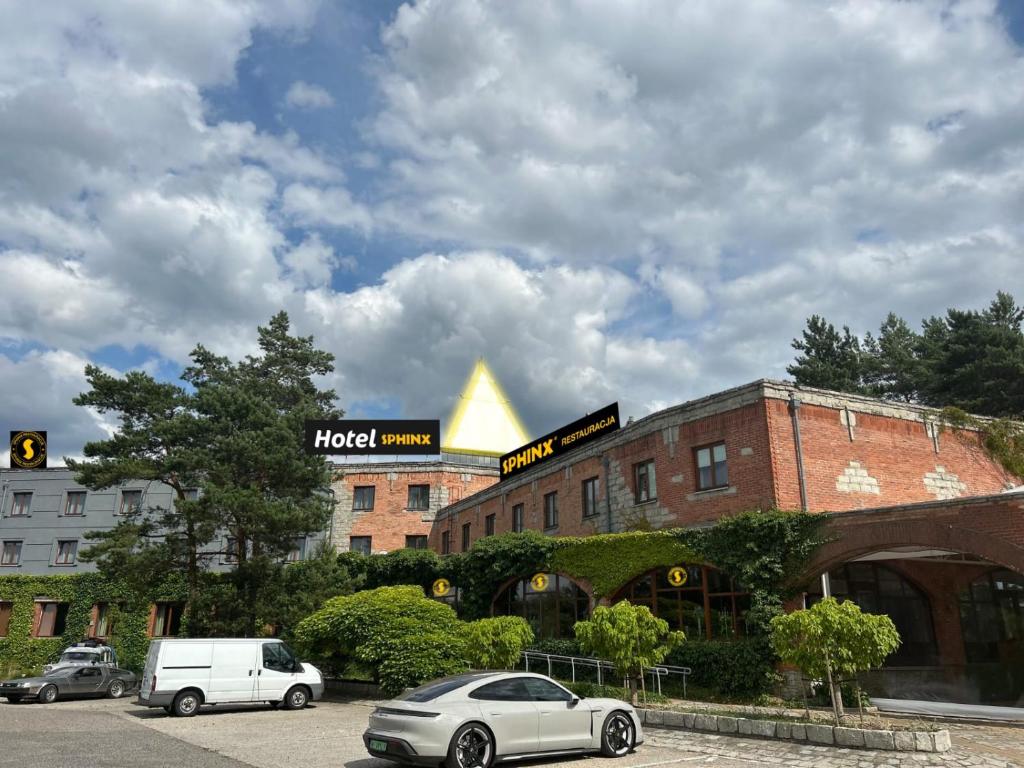 un bâtiment avec des voitures garées dans un parking dans l'établissement Hotel Sphinx, à Żabia Wola