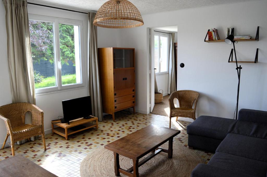 a living room with a couch and a table at La maison de la plage, à 350m de la mer, jardin in Asnelles