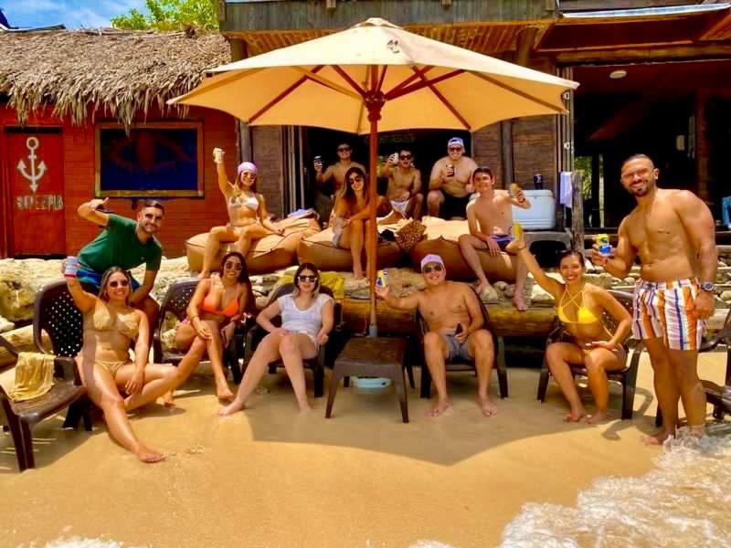 Hotel Prana Beach في بارو: مجموعة من الناس يجلسون تحت مظلة على الشاطئ