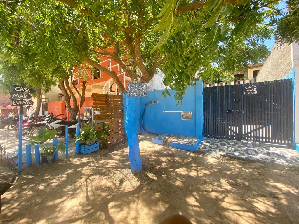 una cerca azul con un árbol delante de un edificio en Casa Mar & Vento 1 en Jericoacoara