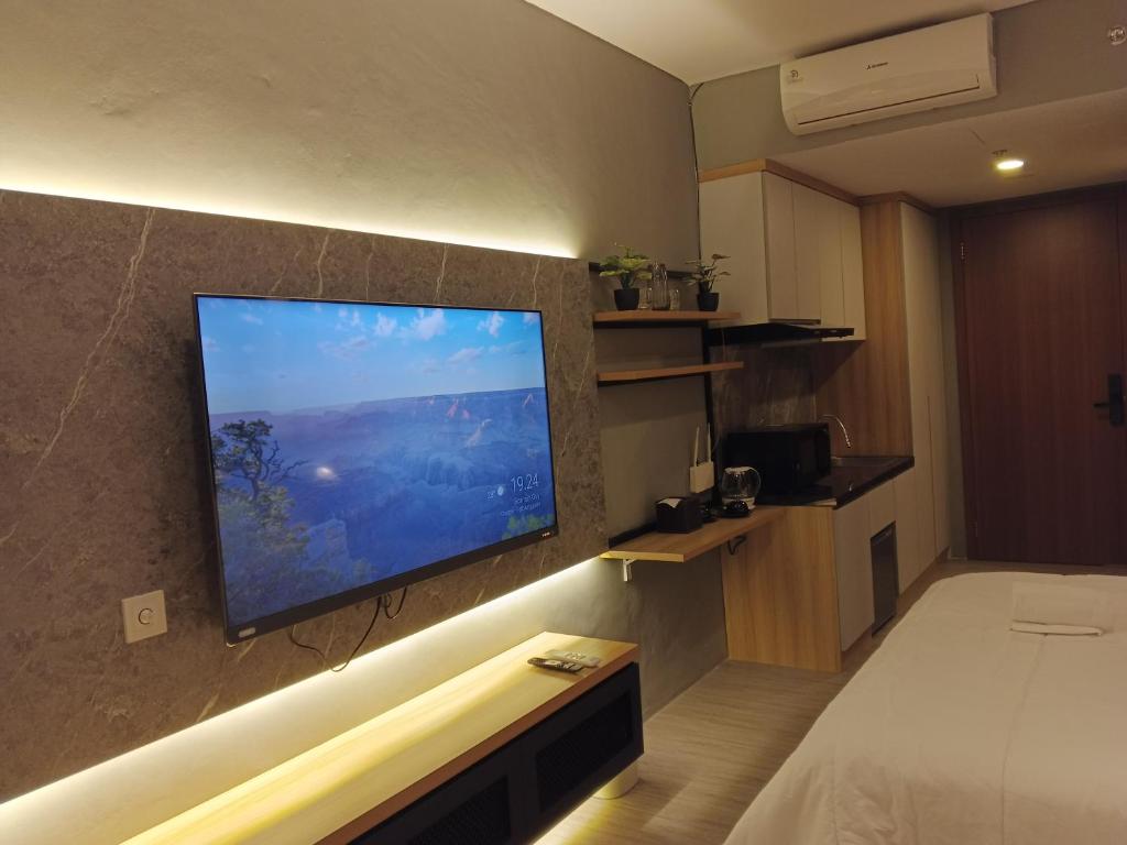 a hotel room with a large flat screen tv on a wall at Free Shuttle Thamrin City Apartments at Nagoya with Netflix & Youtube Premium by MESA in Nagoya
