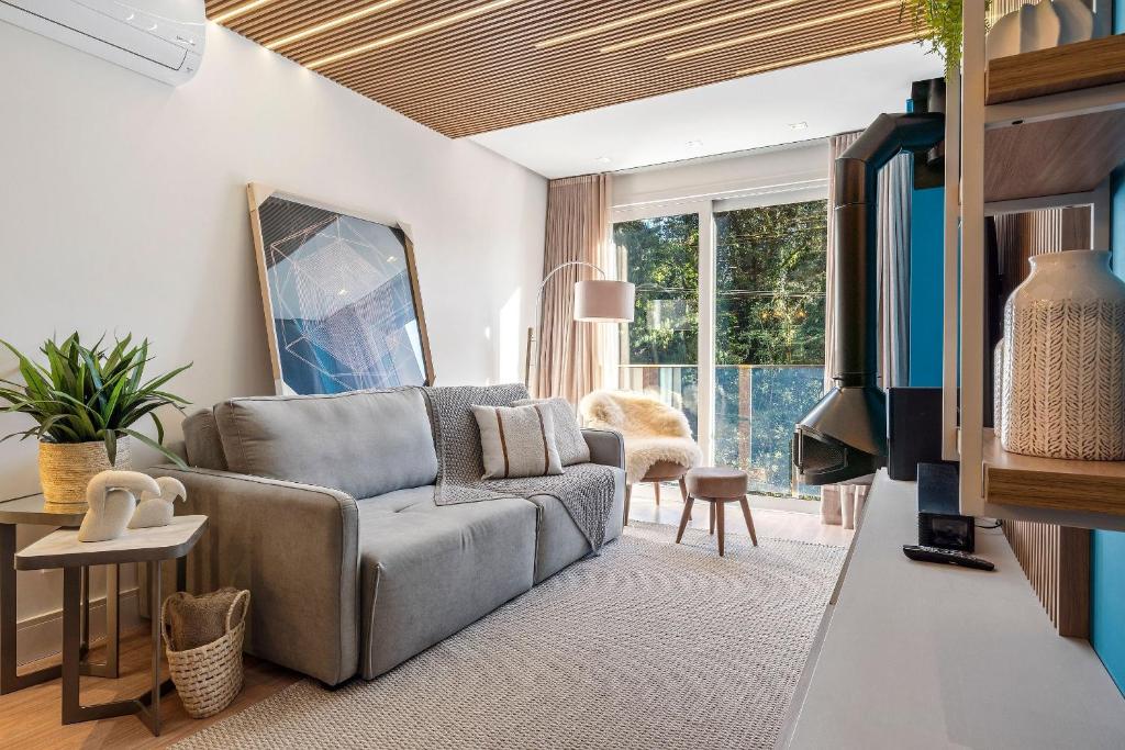 een woonkamer met een bank en een tv bij Apartamento Bellagio 2 Suítes e Piscina by Achei in Canela