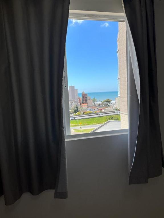 an open window with a view of a city at Apartamento à 380m do Mar in Itapema