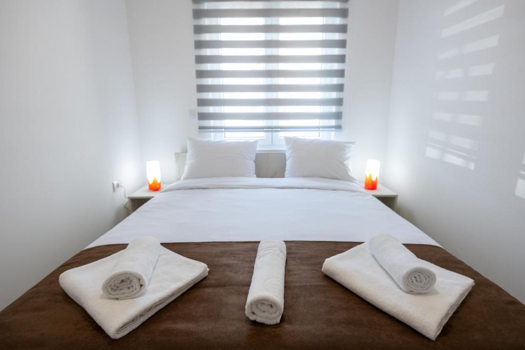 - une chambre avec un grand lit blanc et des serviettes dans l'établissement M&A Apartmani, à Vrdnik
