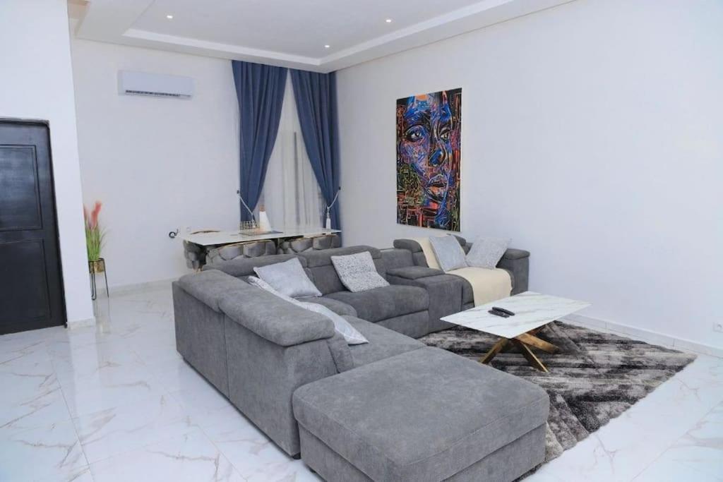 a living room with a gray couch and a table at Appartement Waves au Bord de mer in Cotonou