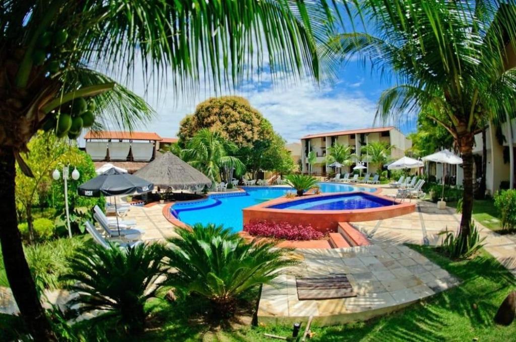 um resort com piscina e palmeiras em Dúplex 2 quartos no coração de Pipa em Pipa
