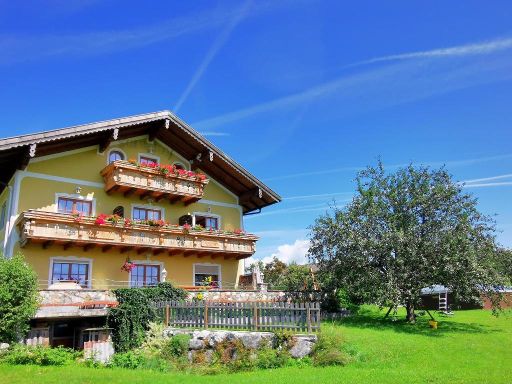 Una gran casa amarilla con balcones y un árbol en Sunnhof, en Oberhofen am Irrsee