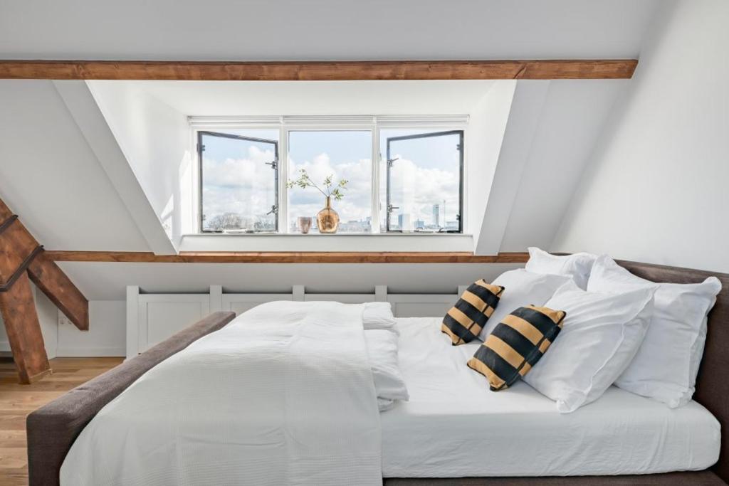 a bedroom with a white bed with pillows and a window at BBWestduin in The Hague