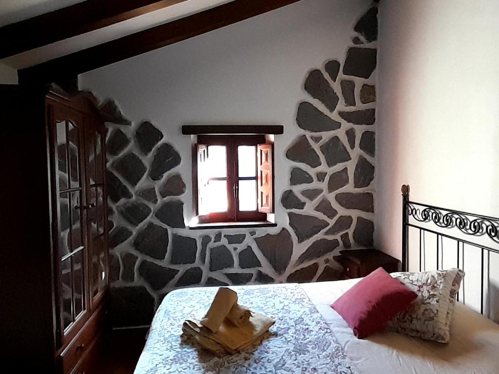 um quarto com uma cama com uma janela e uma parede de pedra em Casa Capricho em Proaza