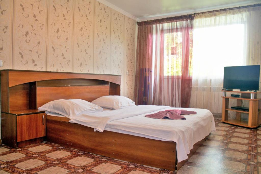 1 dormitorio con 1 cama grande y TV en Мельбурн, en Petropavlovsk