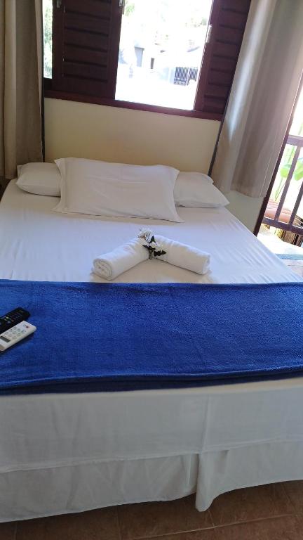 Una cama con sábanas blancas y toallas. en Pousada Flor D' Açucena, en Natal