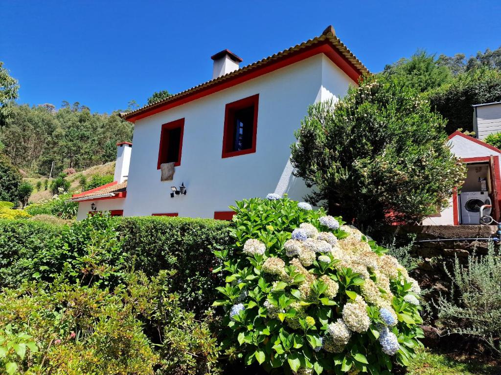 a white house with red windows and some bushes at One bedroom villa with furnished garden and wifi at Camacha in Camacha