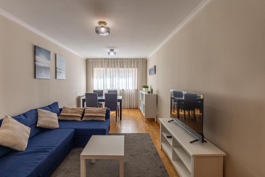 a living room with a blue couch and a tv at Porto FishLand Apartment in Matosinhos