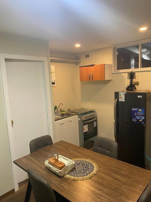 a kitchen with a wooden table and a black refrigerator at Mini casa aérea in Villarrica