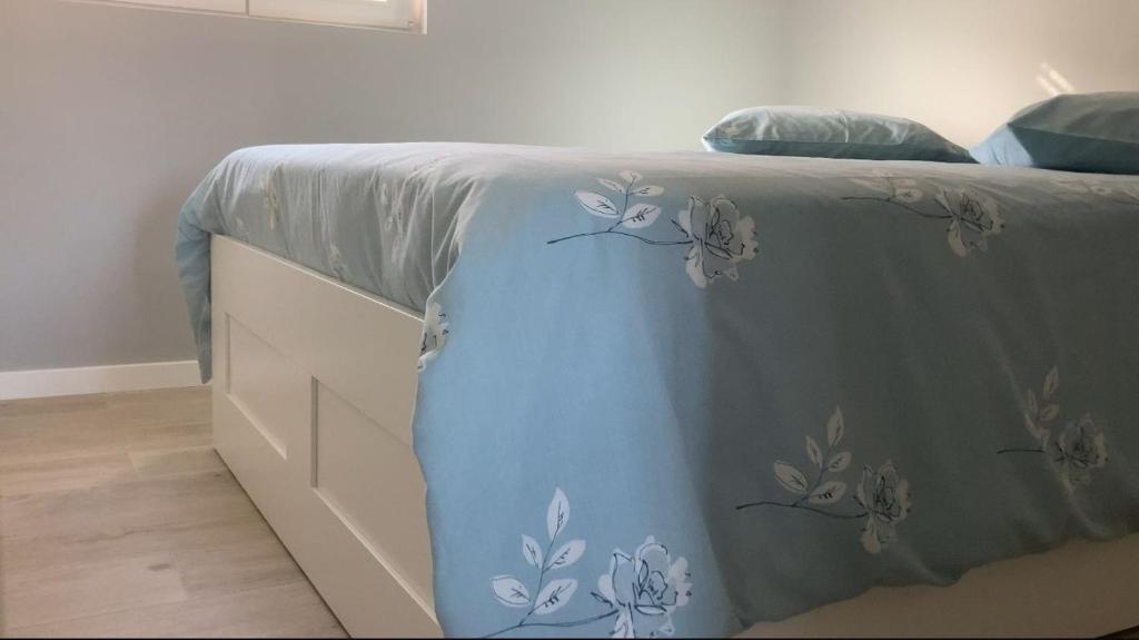 Una cama con una manta azul con flores. en Casa da Ilha Granjal Treixedo, 