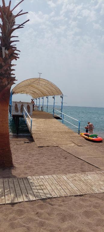 a pier with a person on a surfboard on the beach at Karavan tosbik in Lara