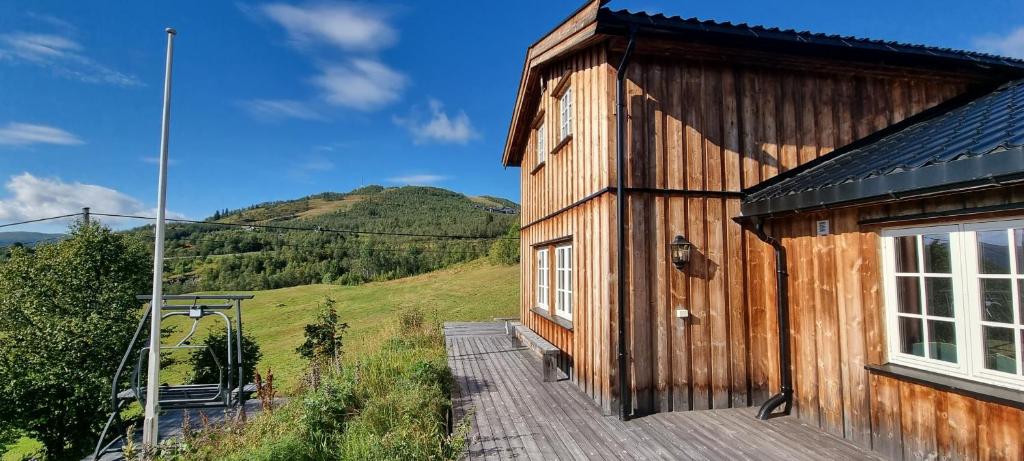 uma casa de madeira com um deque ao lado de uma montanha em Solrik og flott hytte i Havsdalen em Geilo