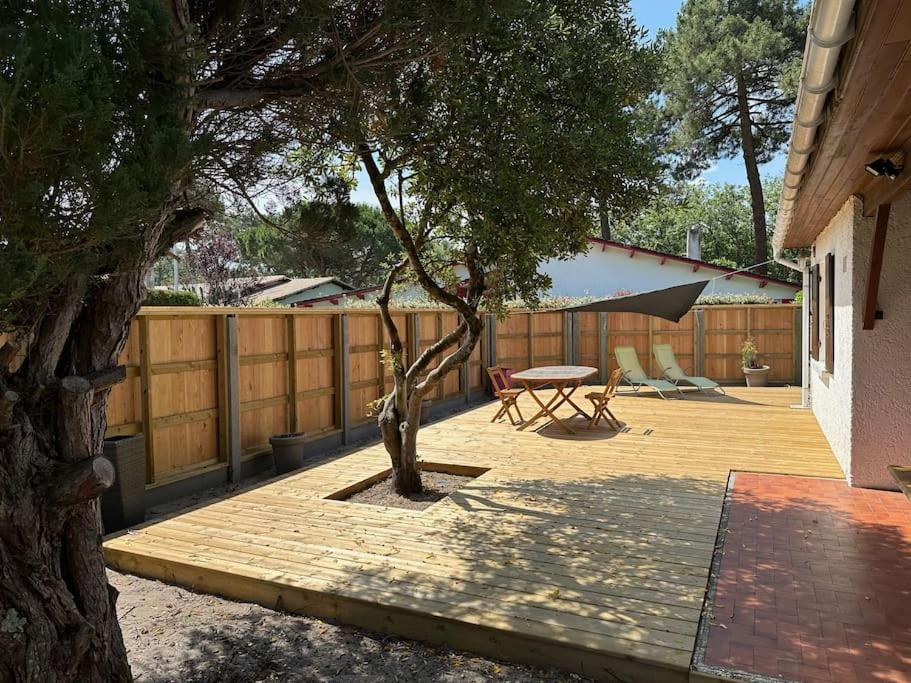 une terrasse avec un arbre, une table et une clôture dans l'établissement Maison Indépendante Bass Arcachon 10min pied plage, à Arès