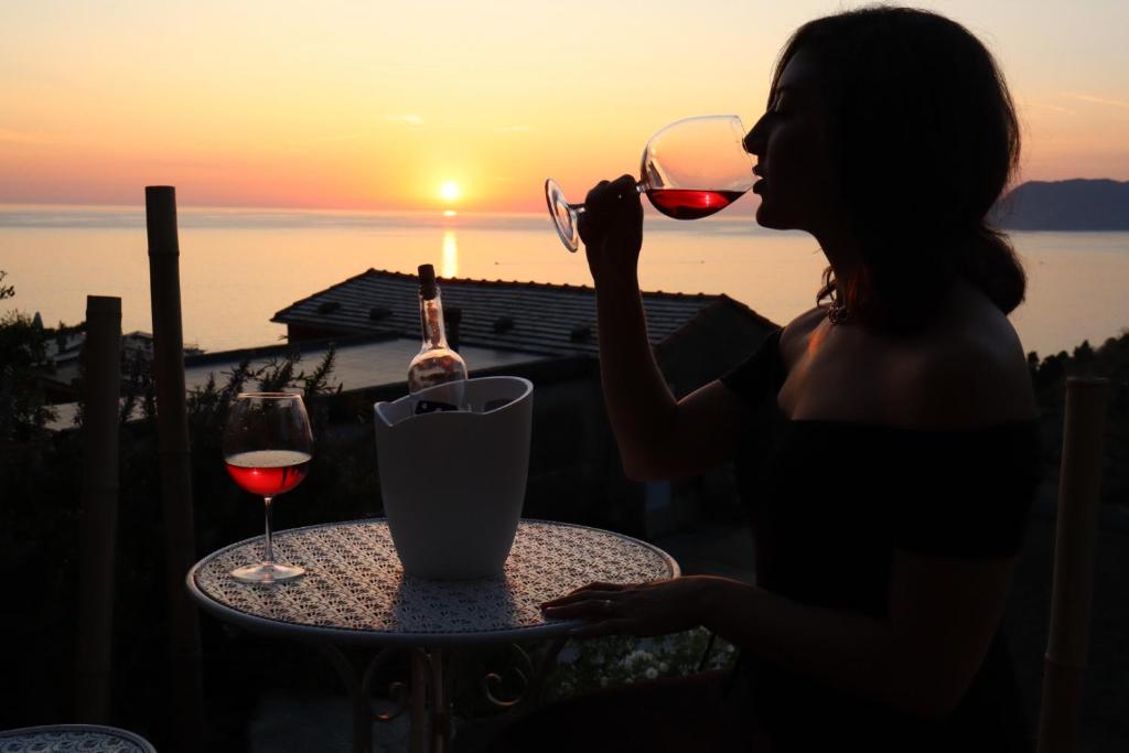Eine Frau, die mit einem Glas Wein am Tisch sitzt. in der Unterkunft Sunset Manarola in Manarola