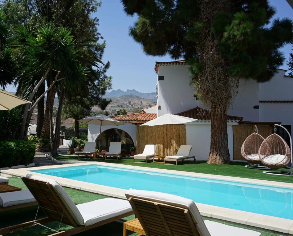 a swimming pool with chairs and a house at Hotel Rural Villa del Monte in Santa Brígida