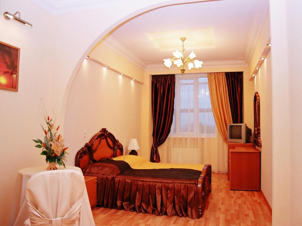 a bedroom with a bed and an arched mirror at Moy Uyutniy Dom Hotel in Kurgan