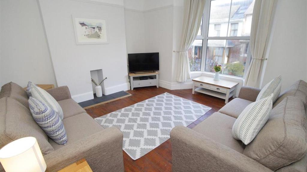 a living room with a couch and a television at Oakland Road, Mumbles in The Mumbles