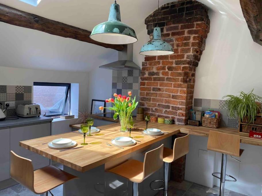 a kitchen with a wooden table and a brick wall at Stylish 3 bedroom apartment in historic city centre building in Sheffield