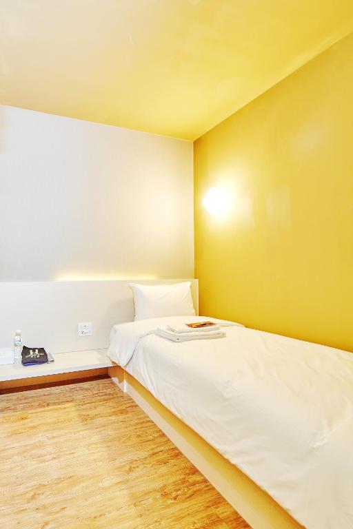 a bedroom with a white bed and a yellow wall at Single Inn - Taipei in Taipei