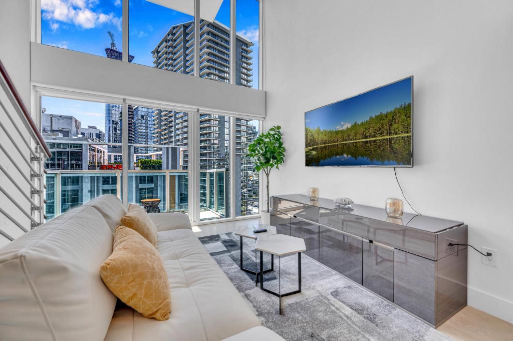 a living room with a white couch and a large window at Stunning 1 Bedroom Loft in The Heart of Brickell in Miami