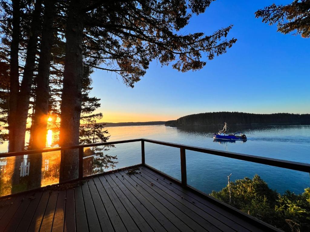 a dock with a boat on a lake at sunset at The Captains View - Cliffside, Ocean Views in Kodiak