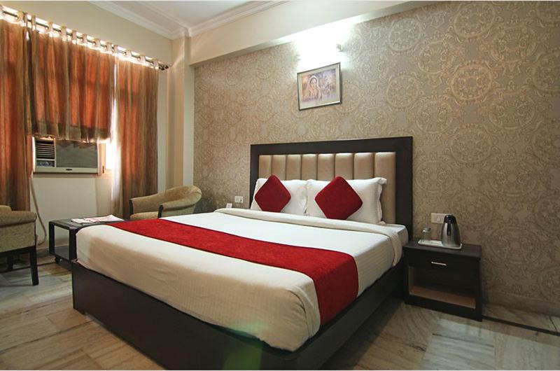 una habitación de hotel con una cama grande con almohadas rojas en Vel Residency, en Thanjāvūr
