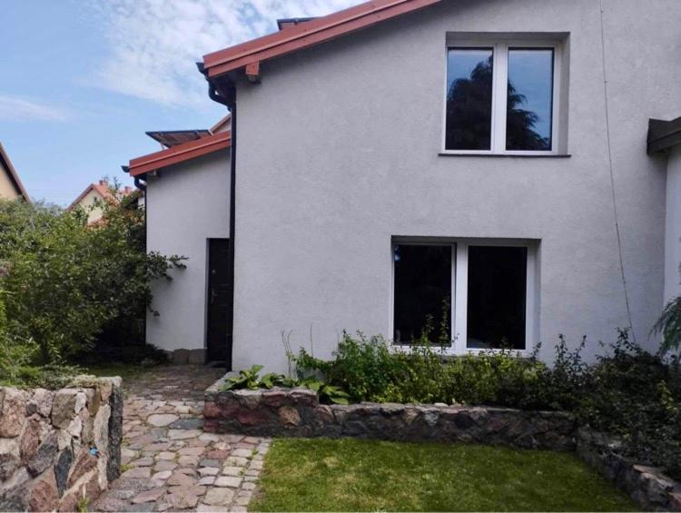 a white house with two windows and a stone path at Domek na Mazurach niedaleko jeziora in Pisz