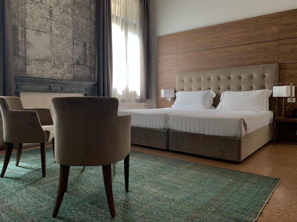- une chambre avec un grand lit et deux chaises dans l'établissement Palazzo Scamozzi, à Vicence