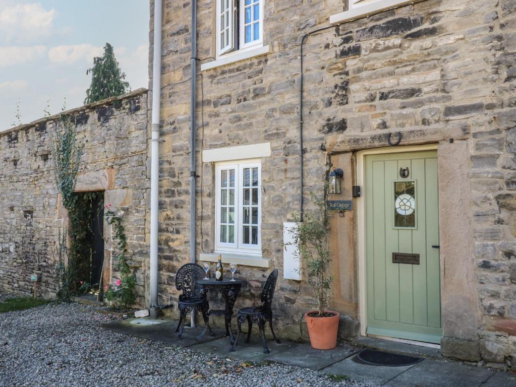 a stone building with a table and chairs next to a door at Teal Cottage in Leyburn