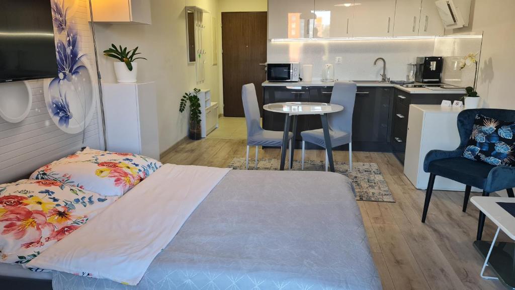 Cette chambre comprend un lit, une table et une cuisine. dans l'établissement Apartament Wyszyńskiego 10, à Białystok